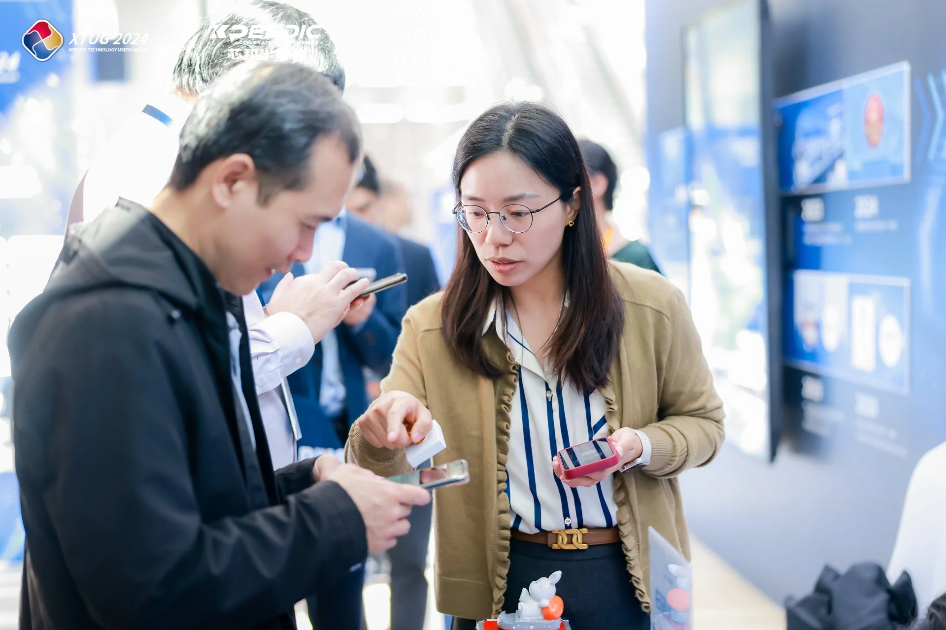 展会现场展台前，两位观众一起用手机查看互动页面